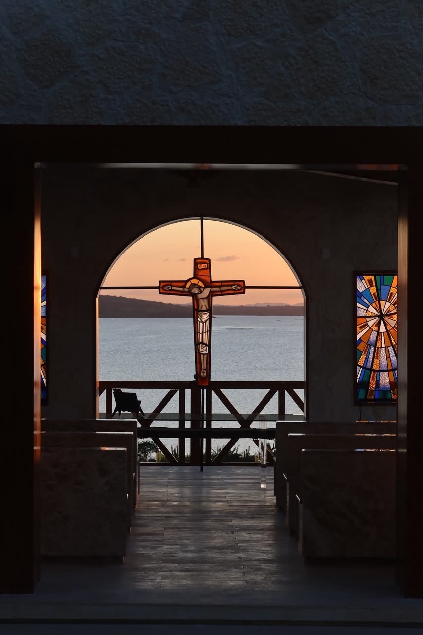 Interior da capela, com a cruz no arco e o lago ao fundo